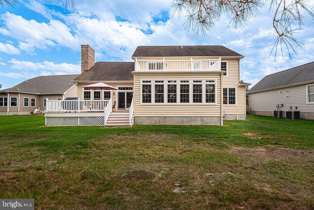 rear view of property featuring a balcony, a chimney, cooling unit, and a yard