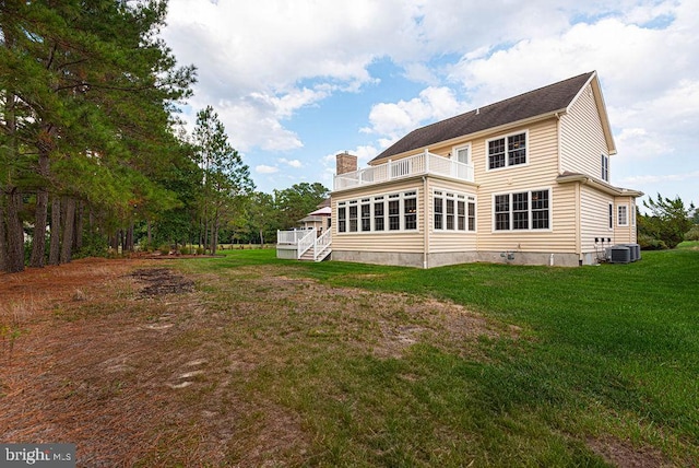 back of property featuring a yard, a chimney, a balcony, and central air condition unit