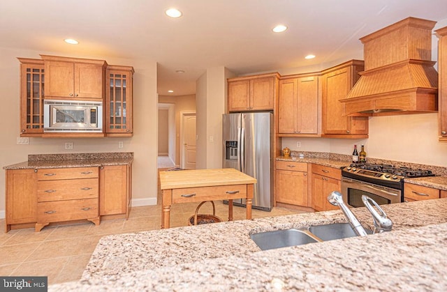 kitchen featuring stainless steel appliances, premium range hood, a sink, and recessed lighting