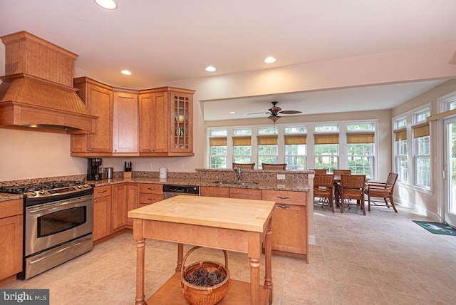 kitchen featuring recessed lighting, a peninsula, a sink, appliances with stainless steel finishes, and brown cabinets