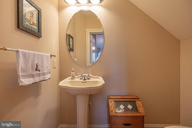 half bath featuring vaulted ceiling and a sink