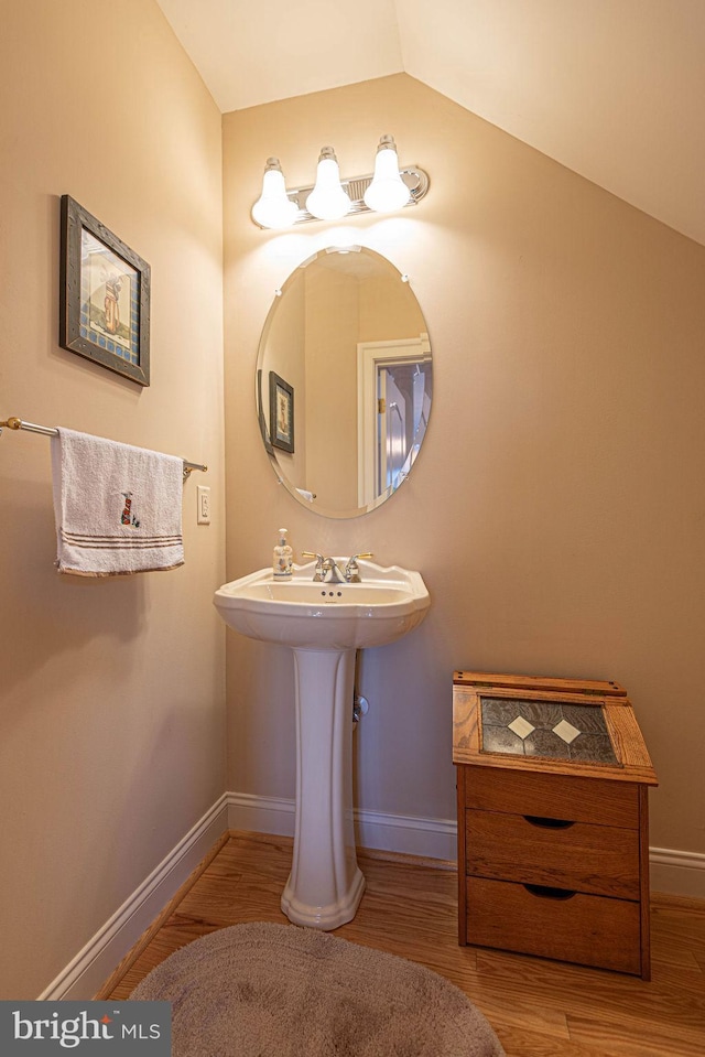 bathroom with lofted ceiling, baseboards, and wood finished floors