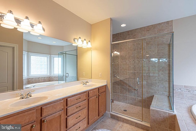 bathroom with a garden tub, tile patterned flooring, and a sink