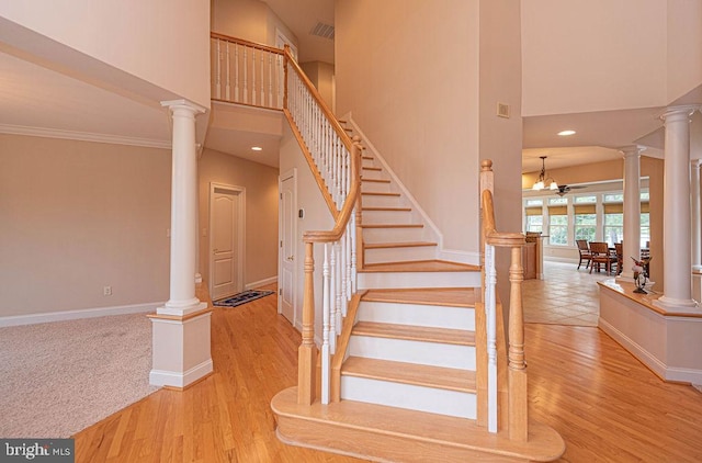 staircase featuring a towering ceiling, visible vents, and ornate columns