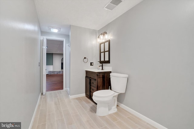 bathroom with visible vents, toilet, vanity, and baseboards