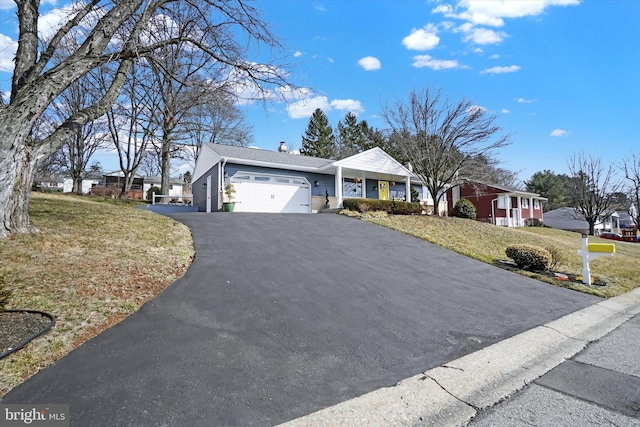 ranch-style house with driveway, a front yard, a chimney, and an attached garage