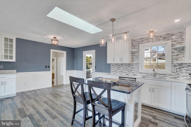 kitchen with white cabinetry, a skylight, a breakfast bar area, and a sink