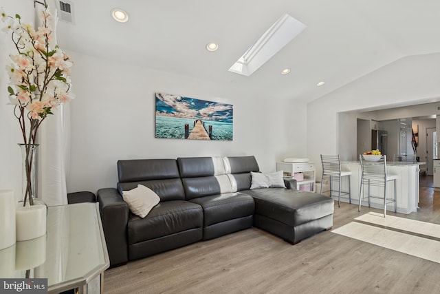 living area with lofted ceiling with skylight, visible vents, light wood finished floors, and recessed lighting