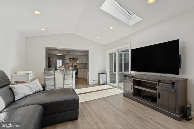 living area featuring lofted ceiling with skylight, light wood-type flooring, baseboards, and recessed lighting