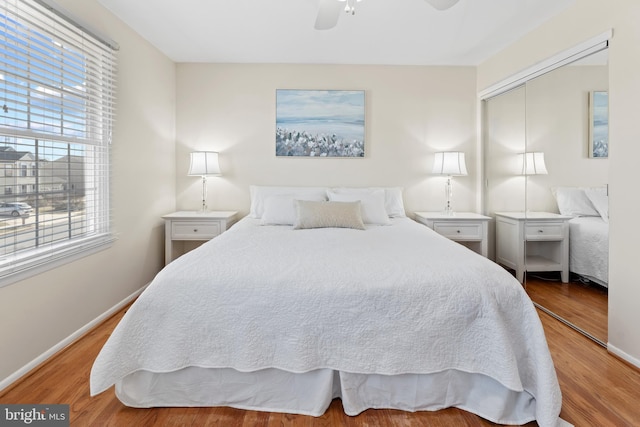 bedroom featuring a ceiling fan, a closet, baseboards, and wood finished floors