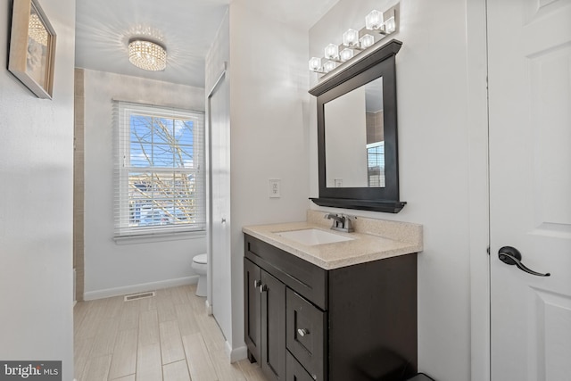 bathroom with baseboards, visible vents, vanity, and toilet