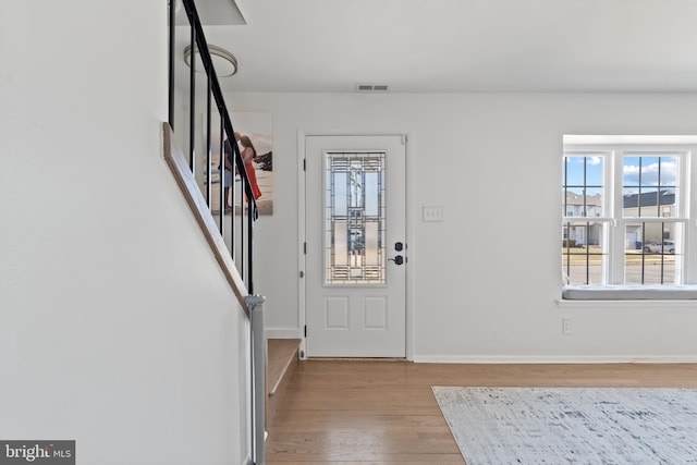 entrance foyer with stairs, visible vents, baseboards, and wood finished floors