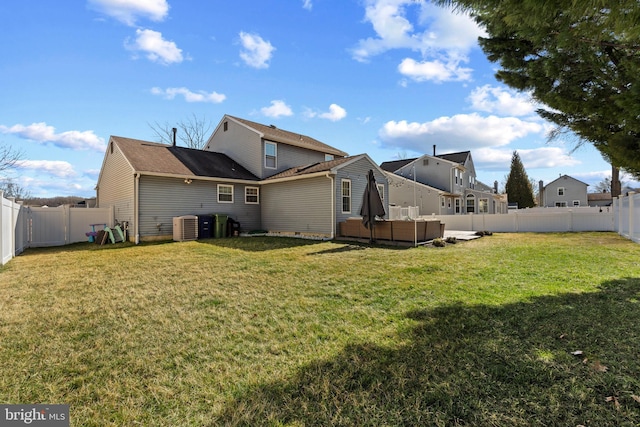 back of property with central air condition unit, a fenced backyard, and a lawn