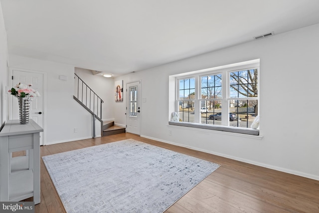 foyer entrance featuring stairs, wood finished floors, visible vents, and baseboards