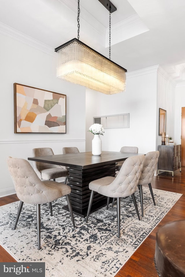 dining room with ornamental molding, a raised ceiling, and wood finished floors