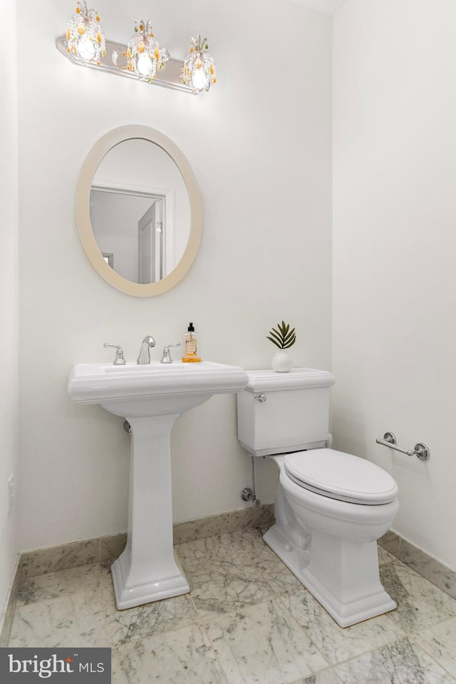 half bath featuring marble finish floor, baseboards, and toilet