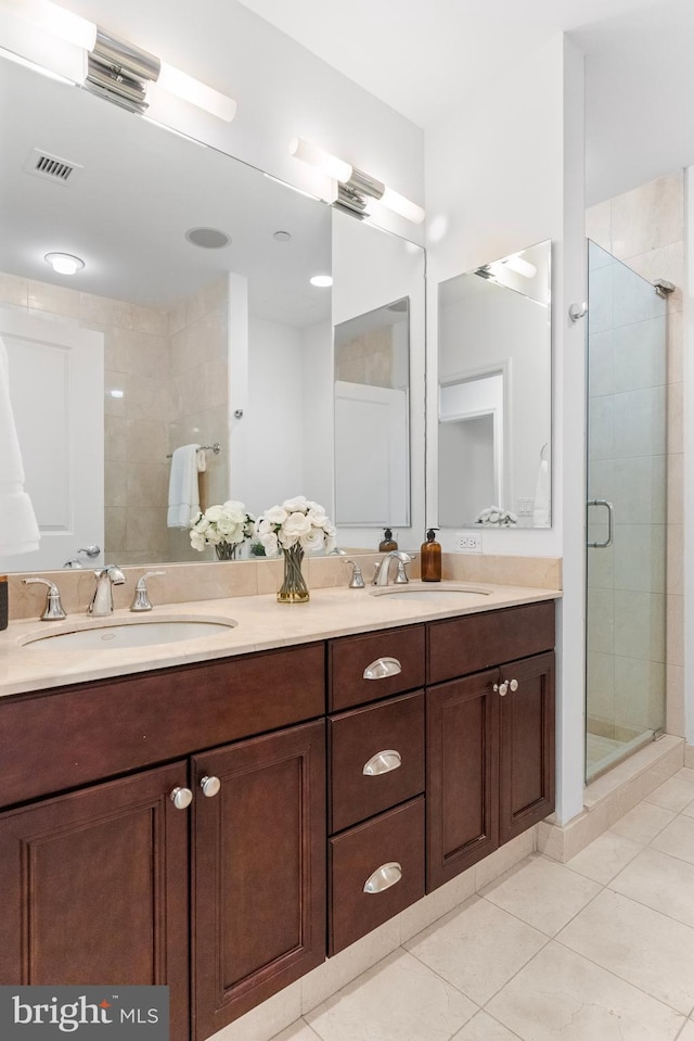 bathroom featuring double vanity, tile patterned flooring, a sink, and a shower stall