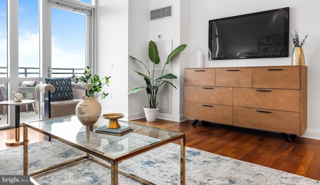 living room featuring dark wood-style flooring, visible vents, and baseboards