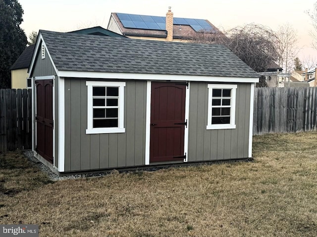 view of shed featuring solar panels and fence