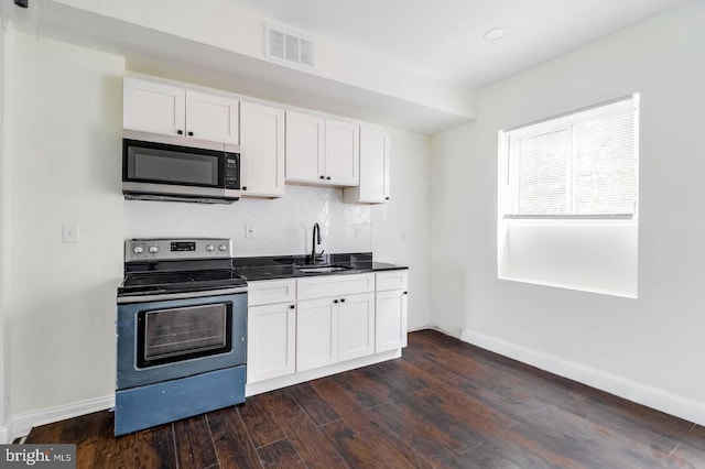 kitchen with visible vents, dark wood-style floors, stainless steel appliances, white cabinetry, and a sink