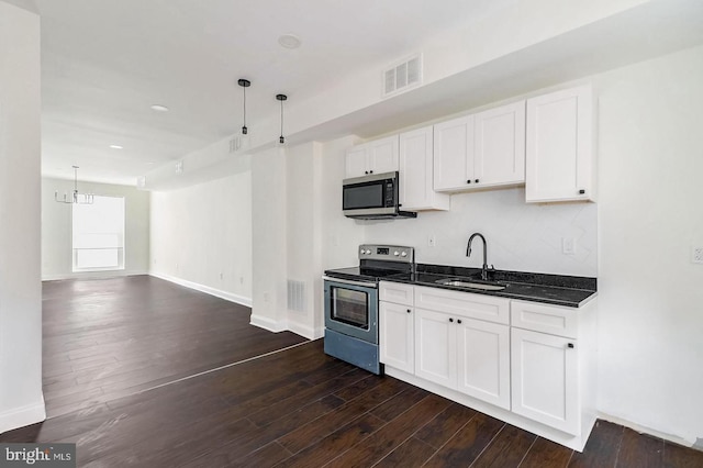 kitchen with appliances with stainless steel finishes, dark wood-type flooring, a sink, and visible vents