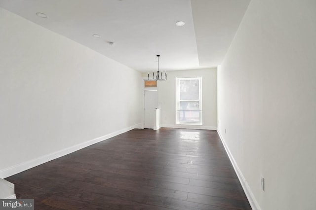 interior space featuring dark wood finished floors, baseboards, and an inviting chandelier