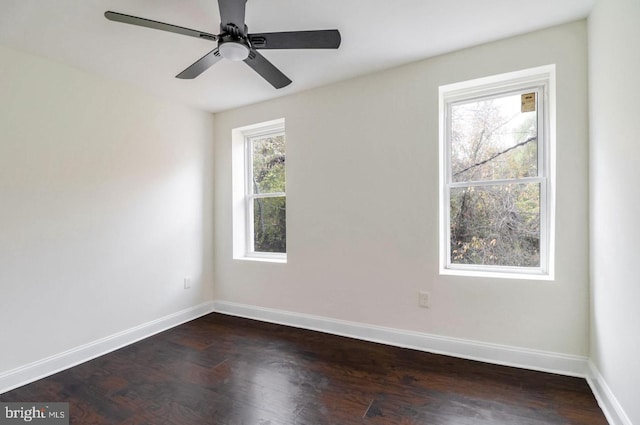 empty room with dark wood-style floors, a ceiling fan, and baseboards