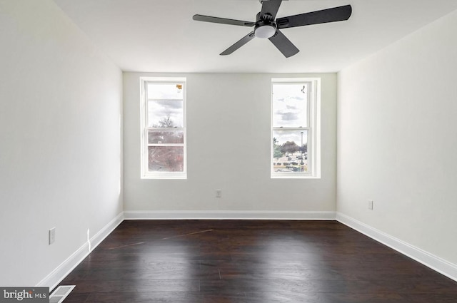 spare room with a ceiling fan, visible vents, baseboards, and wood finished floors