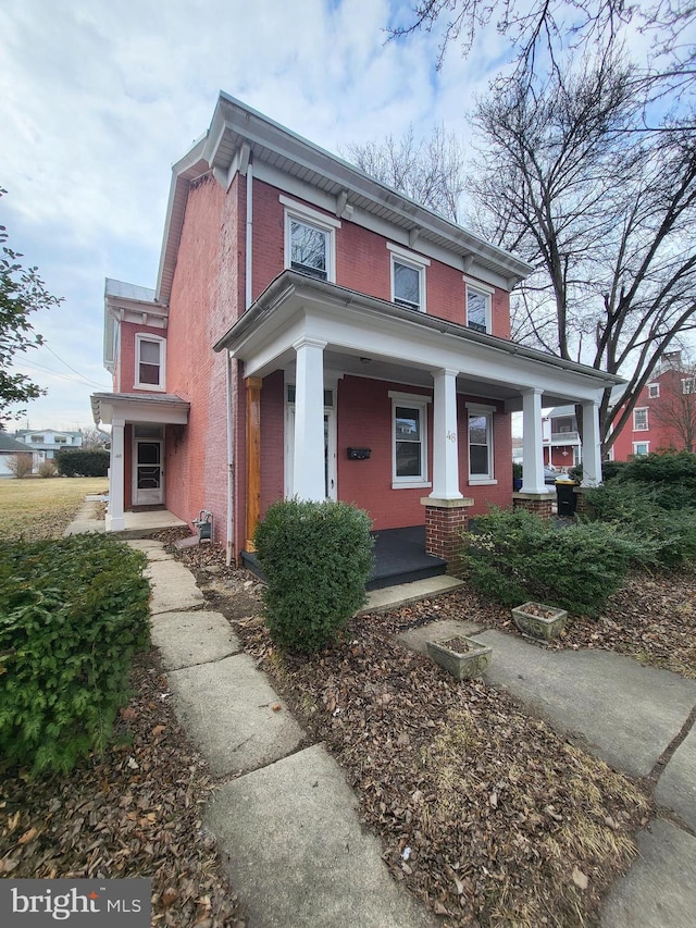 italianate house featuring brick siding and a porch