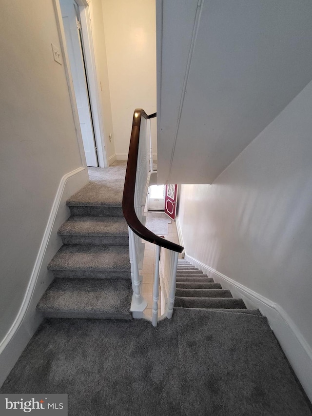 stairway with baseboards and carpet flooring