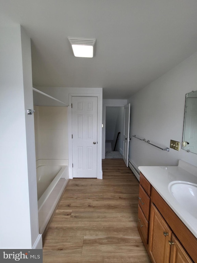 full bath with shower / bath combination, a baseboard radiator, wood finished floors, and vanity