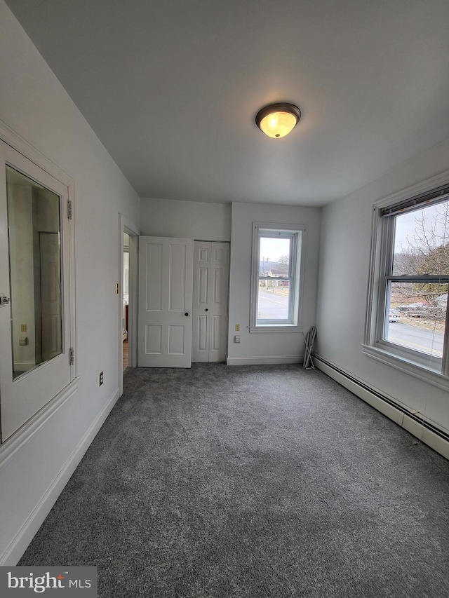 unfurnished bedroom with a closet, carpet, a baseboard radiator, and baseboards