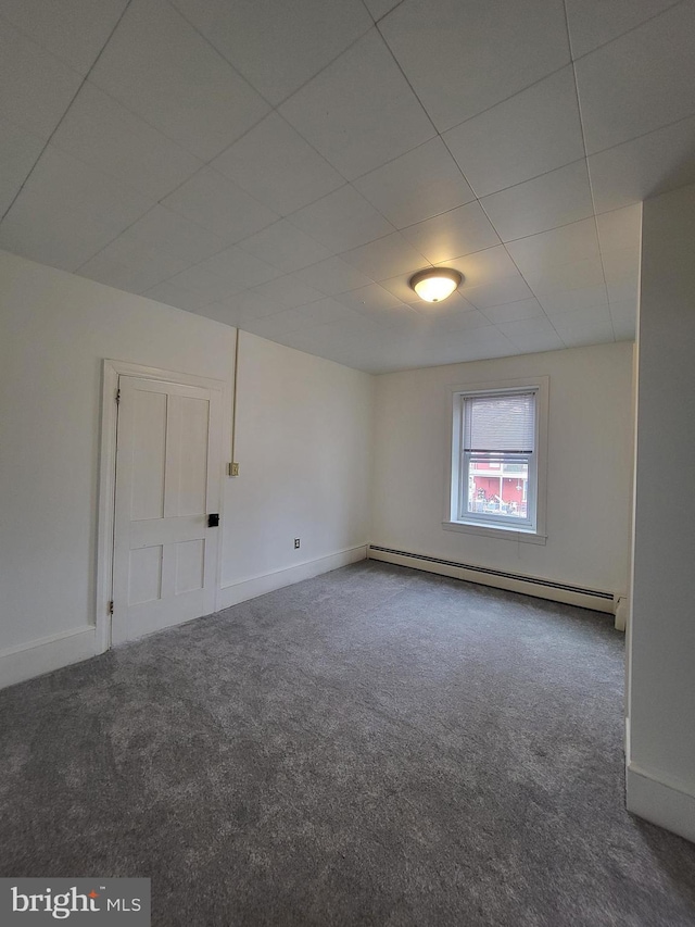 carpeted empty room with a baseboard heating unit and baseboards