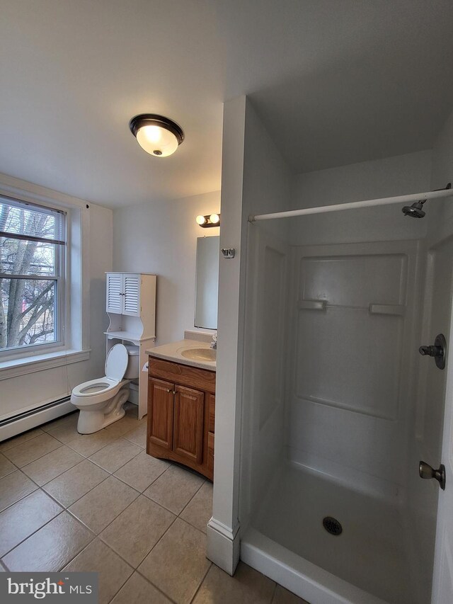 full bathroom with a baseboard heating unit, a stall shower, vanity, and tile patterned floors