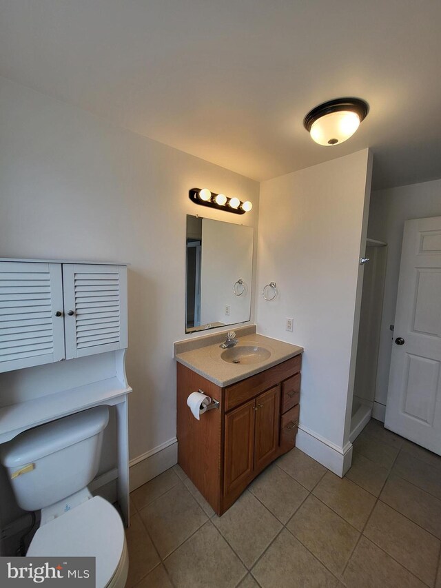 full bathroom with toilet, a shower stall, vanity, tile patterned flooring, and baseboards