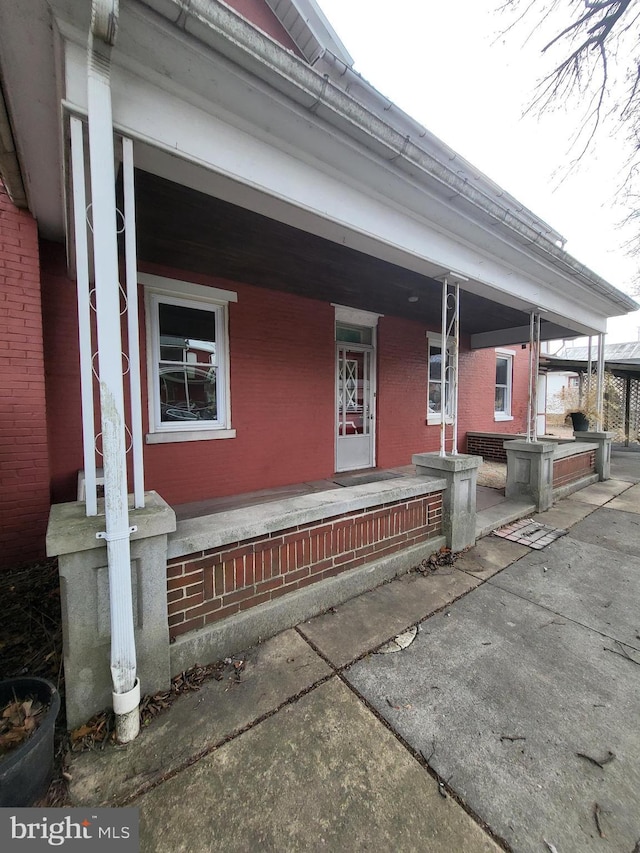 exterior space with a porch and brick siding