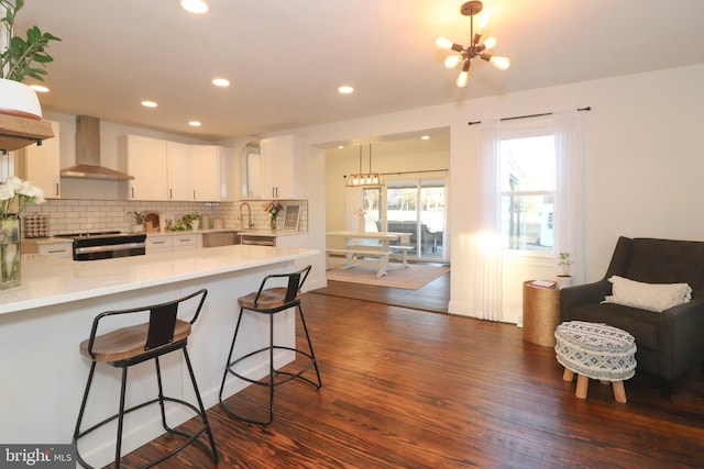 kitchen with a chandelier, dark wood-style flooring, black range with electric cooktop, and wall chimney range hood