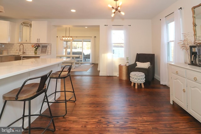 kitchen with a chandelier, tasteful backsplash, dark wood-style floors, and a kitchen breakfast bar