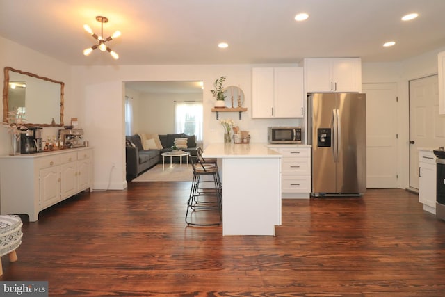 kitchen with stainless steel appliances, light countertops, a kitchen breakfast bar, and dark wood-style floors