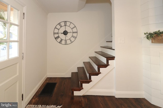 stairs with crown molding, wood finished floors, visible vents, and baseboards