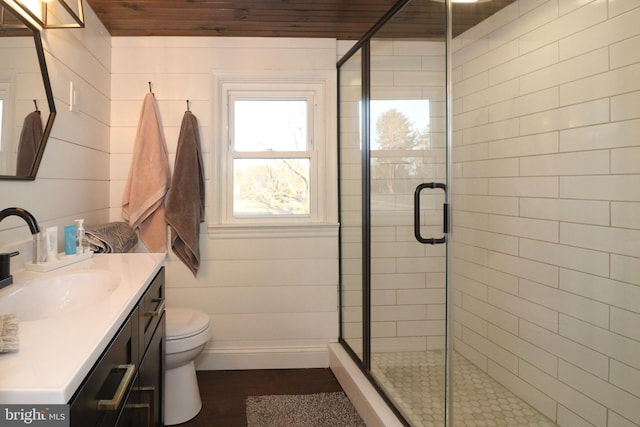 full bathroom with a stall shower, vanity, toilet, and wood finished floors