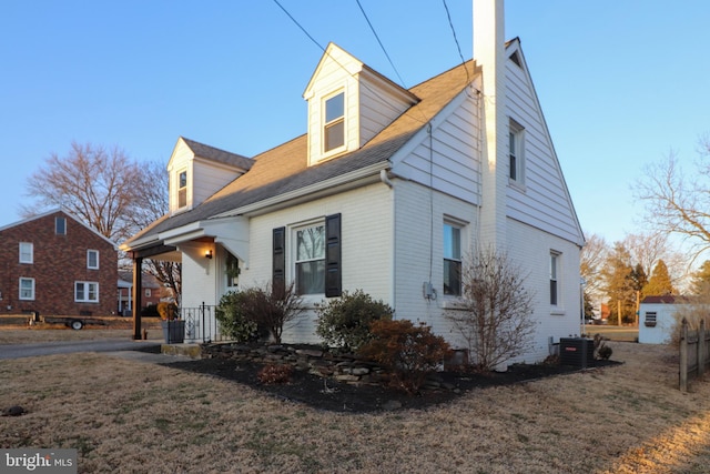 view of front of house with a chimney, cooling unit, and a front yard