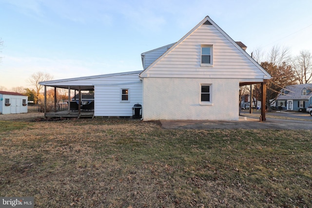 back of house at dusk with a shed, an outbuilding, a lawn, and brick siding