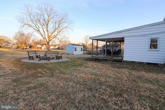 view of yard with an outdoor structure, a fire pit, a storage shed, and fence