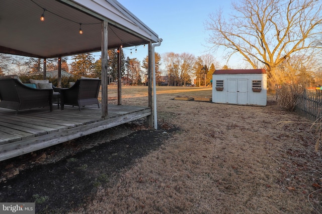 view of yard with a shed, fence, a wooden deck, and an outdoor structure