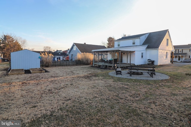 back of property featuring a lawn, an outdoor structure, and fence