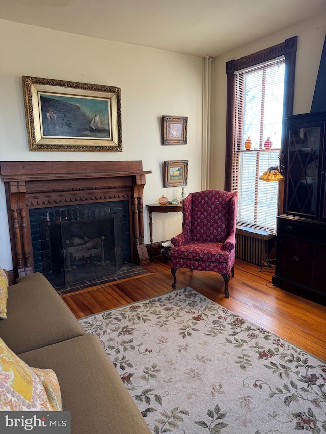 living room featuring radiator, a fireplace with flush hearth, and wood finished floors