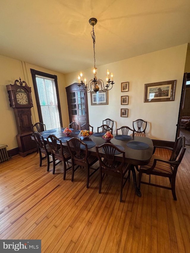 dining space featuring light wood-style flooring, baseboards, and an inviting chandelier