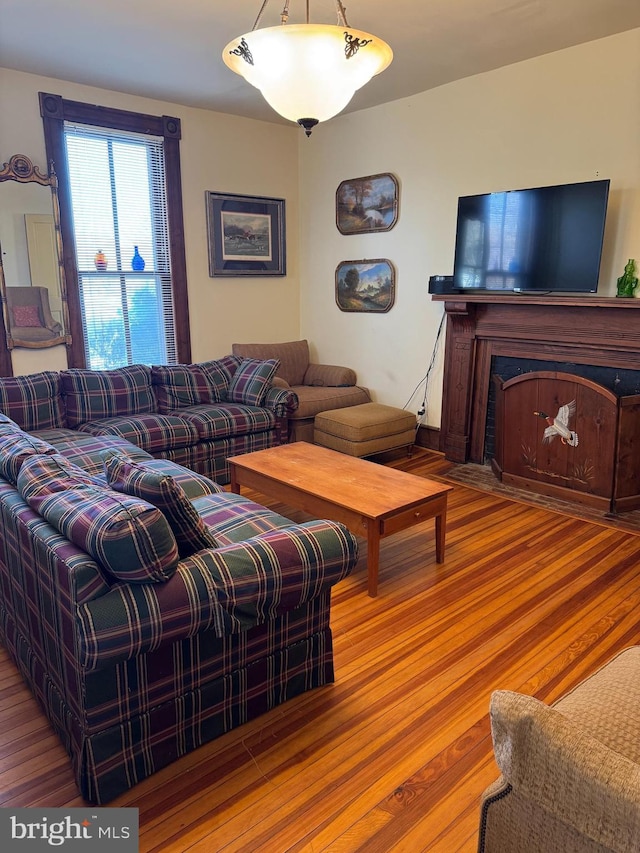 living area with a fireplace with flush hearth and wood finished floors