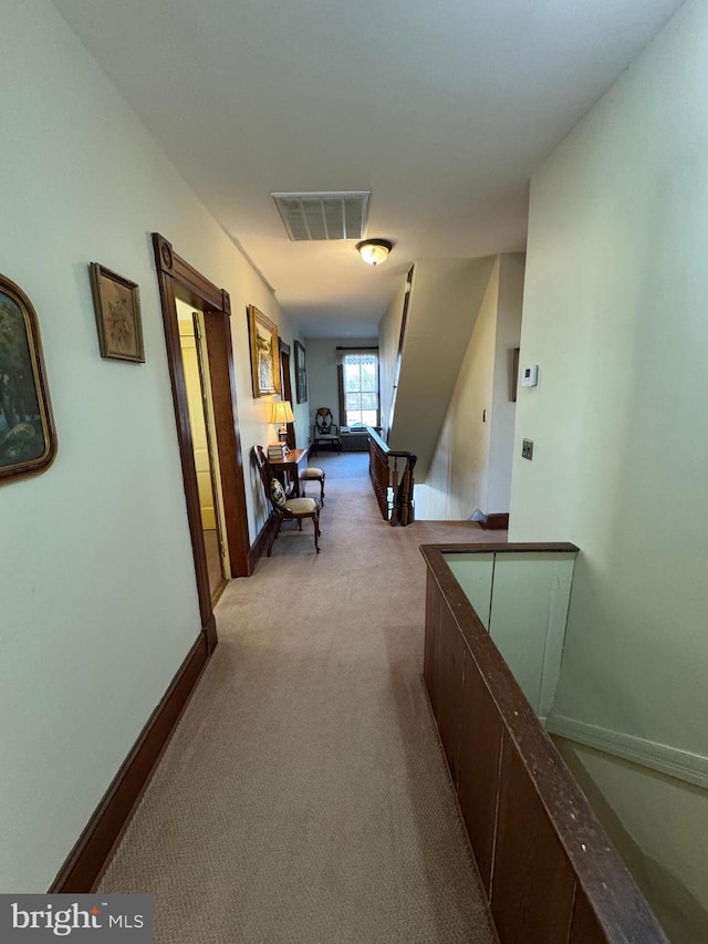 hallway featuring carpet flooring, visible vents, and baseboards